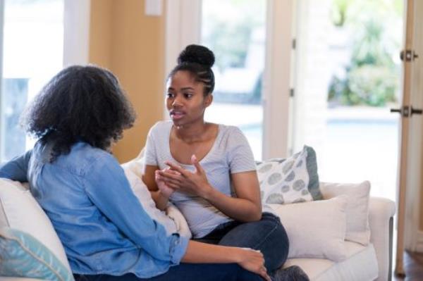 woman sitting on a couch with a friend, nervous a<em></em>bout apologizing